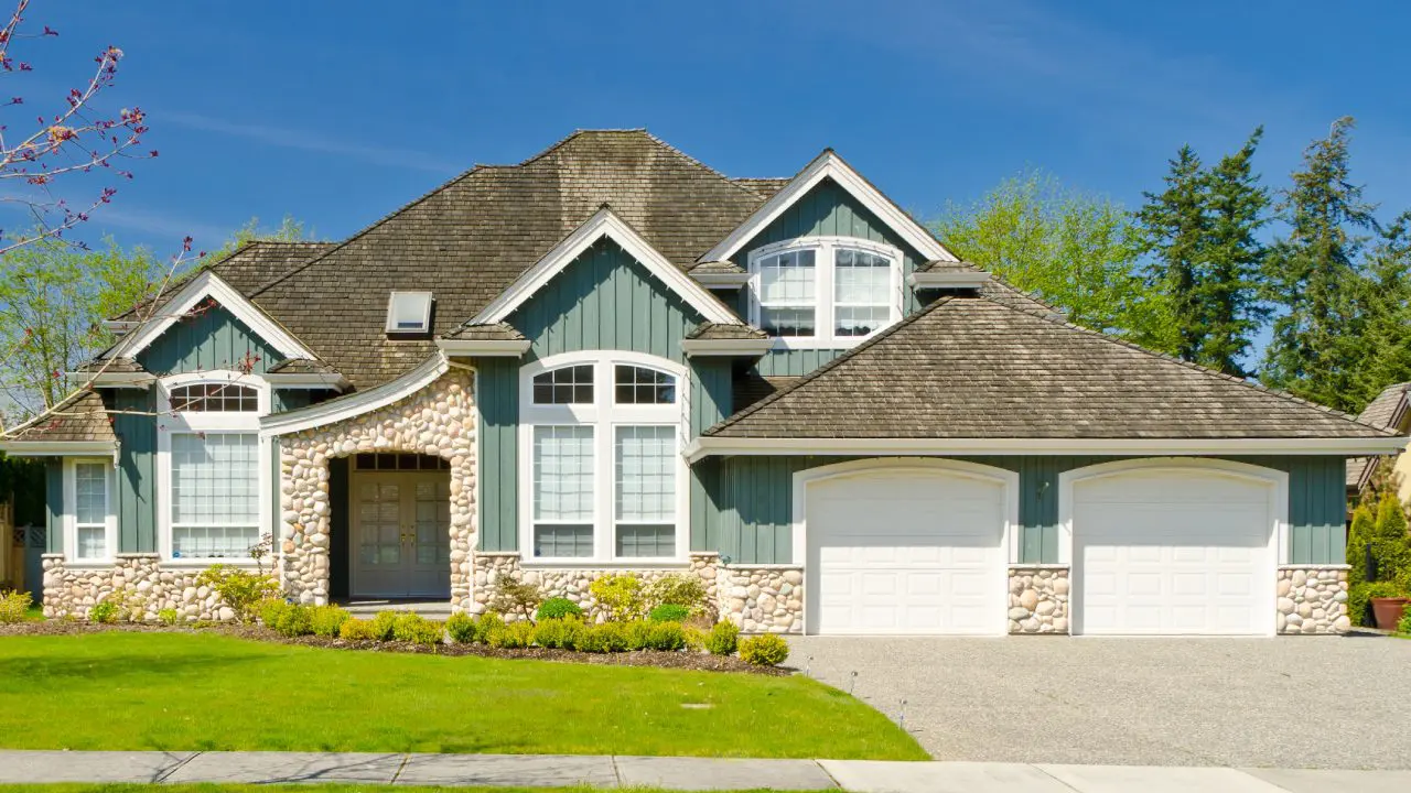 A house with a driveway and lawn in front of it.