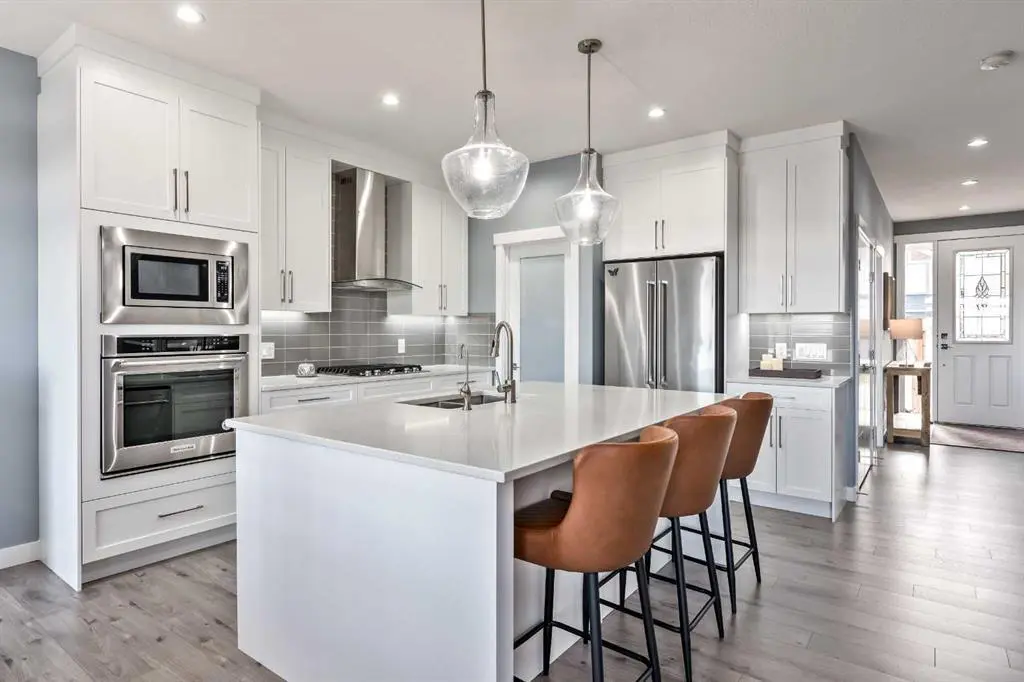 A kitchen with white cabinets and brown chairs